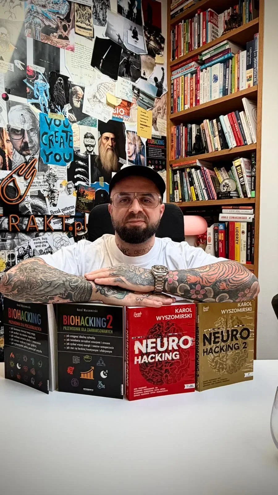 Karol Wyszomirski przy biurku z książkami Biohacking i Neurohacking.